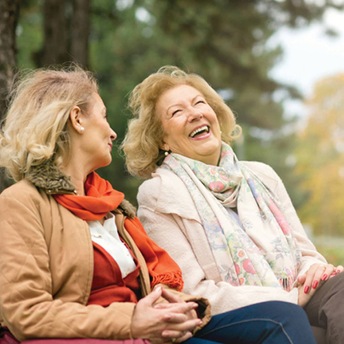 Two women laughing in a park